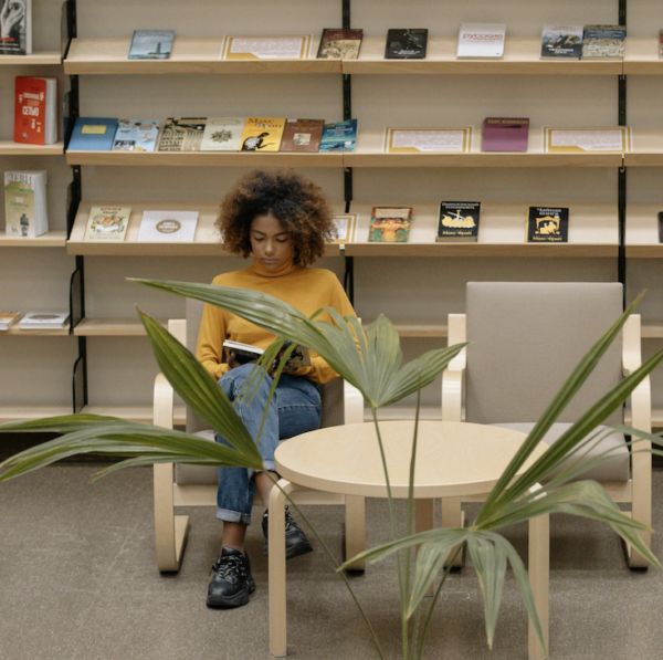 A seated woman reading a book in a library