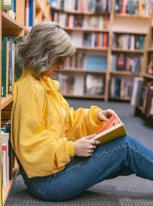 A seated woman reading a book in a library