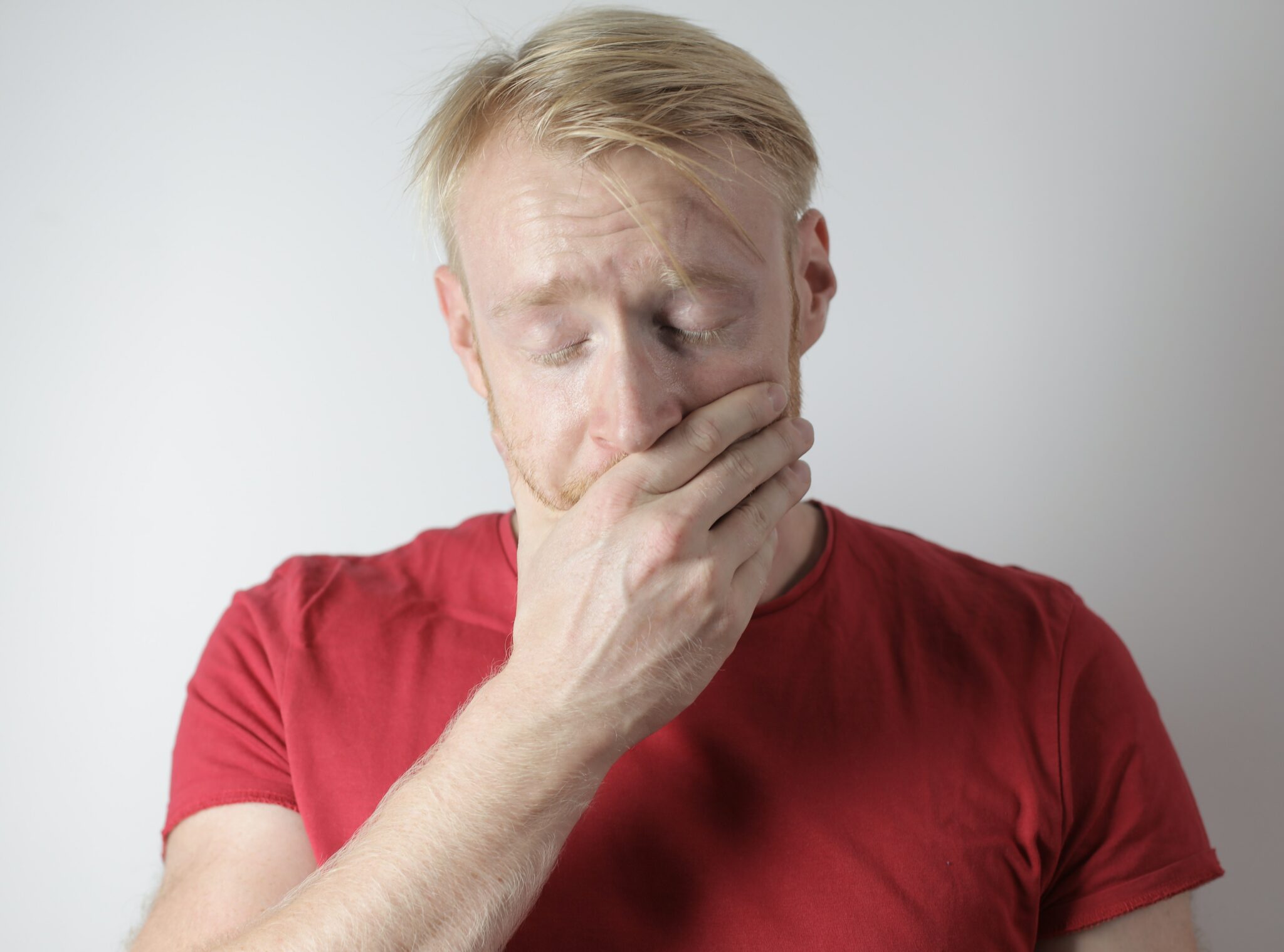 A person holding their hand over their mouth with eyes closed