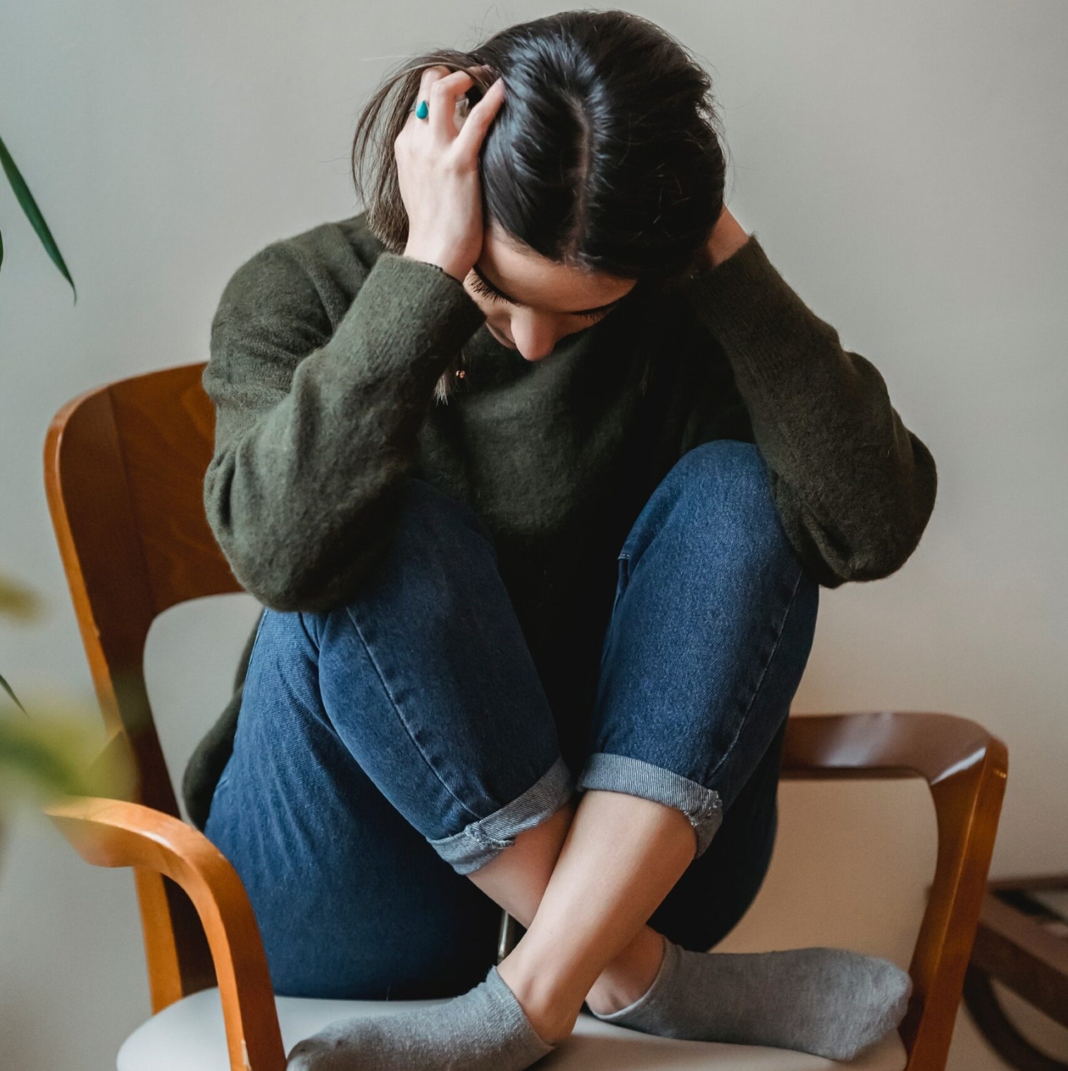 A person with their face down holding her head with both hands